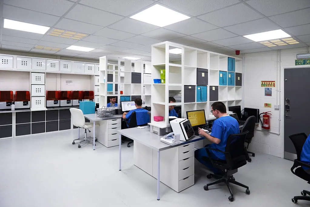Dental laboratory technicians designing restorations at CAD workstations