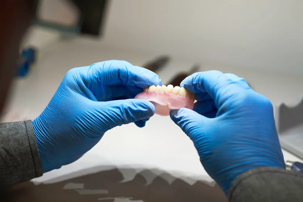 Technician inspecting a 3D-printed denture arch produced from a Euro Dental Design digital file